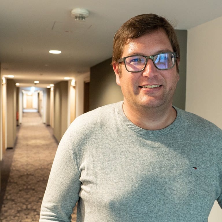 Hotelinhaber Alexander Wurster steht in einem langen, leeren Flur und blick in die Kamera (Foto: SWR)